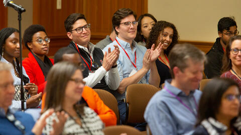 MIP Students smiling and clapping while attending a panel discussion